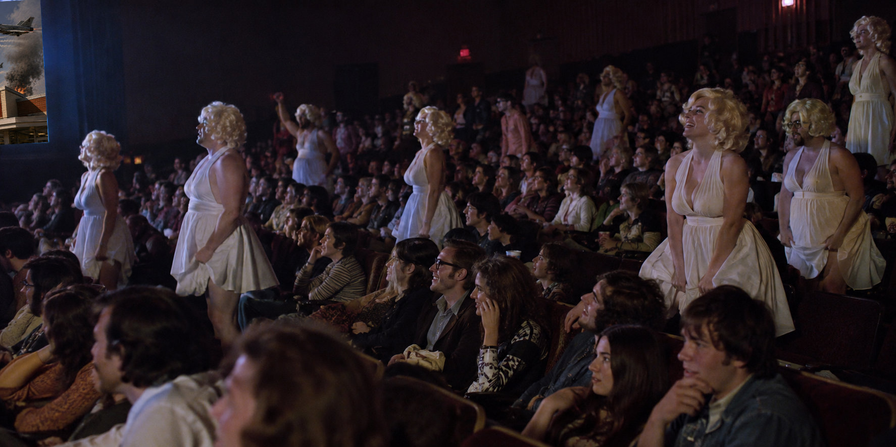 Adult moviegoers in blonde wigs and white dresses stand among the seated midnight audience; some hold their skirts down in homage to Marilyn Monroe.